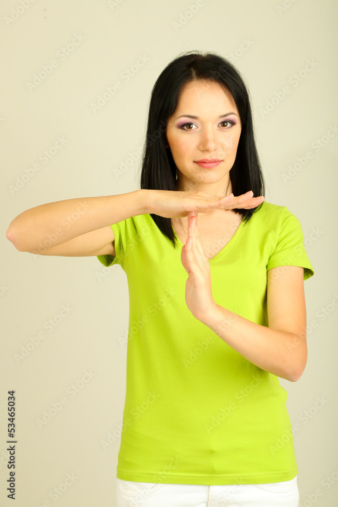 Girl showing time out sign on grey background Girl showing time out sign on grey background