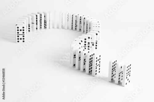 Dominoes in shape of question mark on plain background