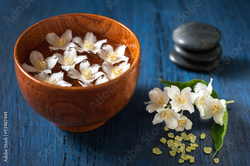 White flowers in a bowl, stones for massage and sea salt. Spa.