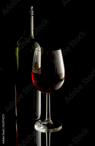 Low key image of red wine in glass with bottle