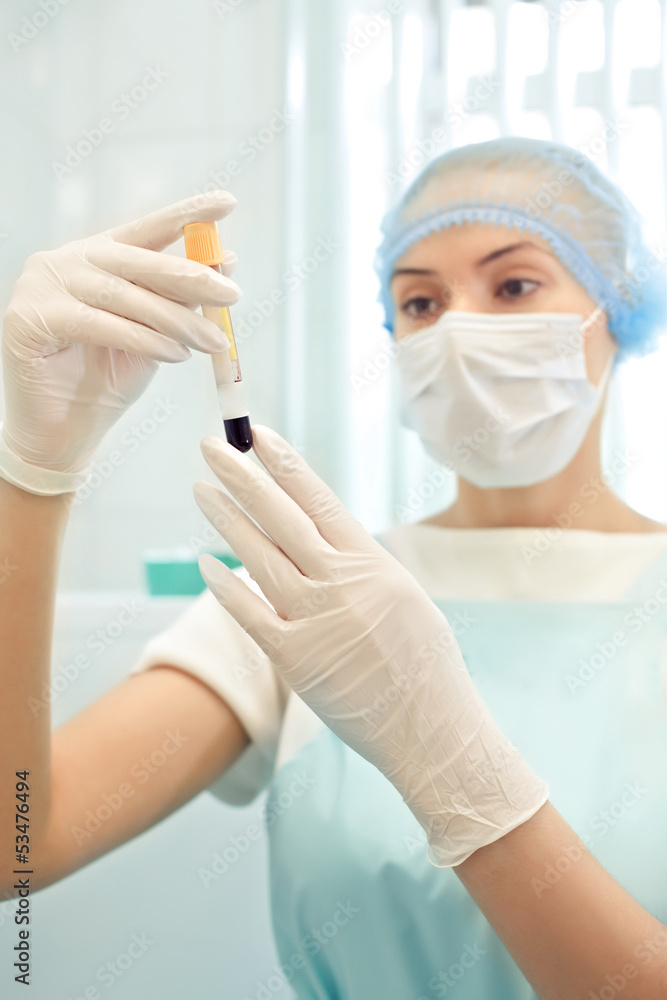 Medical doctor woman looking on test tube with blood Medical doctor woman looking on test tube with blood