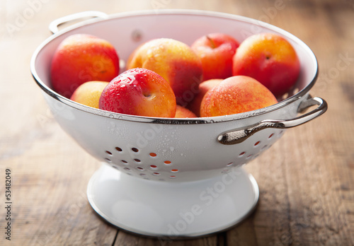 fresh nectarines and plums in colander