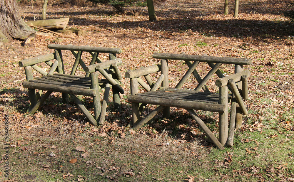 Two Rustic Wooden Seats in a Woodland Setting. Two Rustic Wooden Seats in a Woodland Setting.