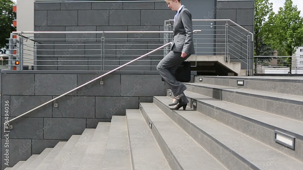 Young woman in business suit walking down staircase in slow moti Young woman in business suit walking down staircase in slow moti