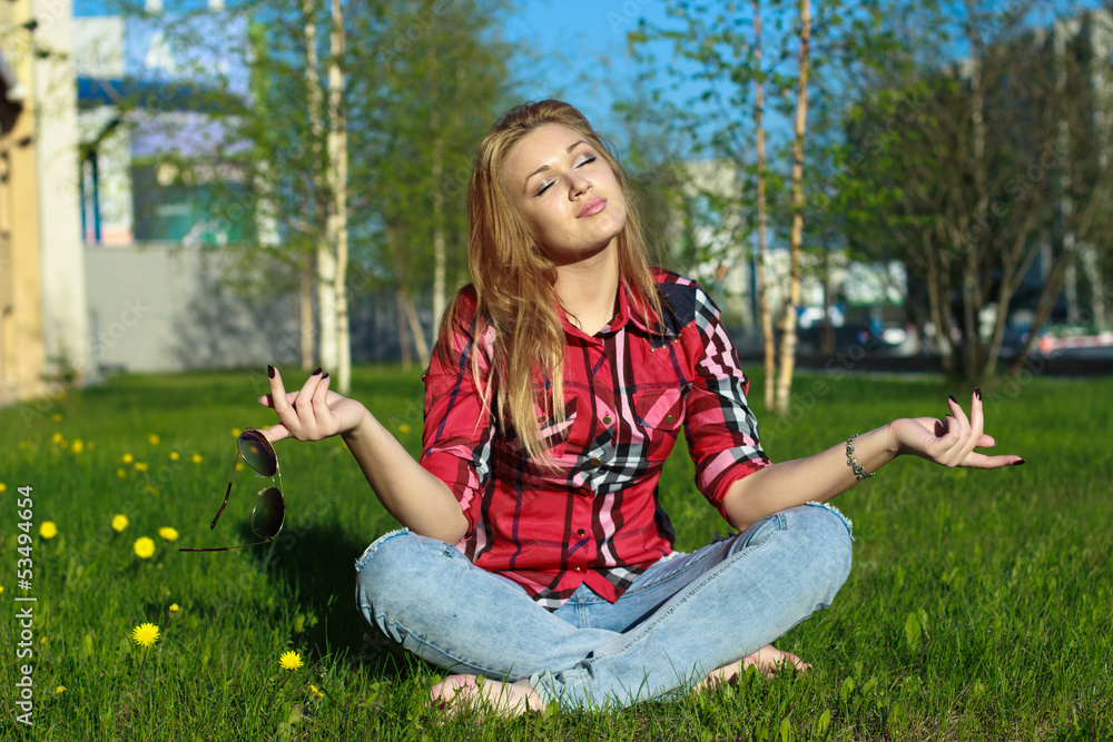 Fototapeta premium Blonde girl meditating on grass