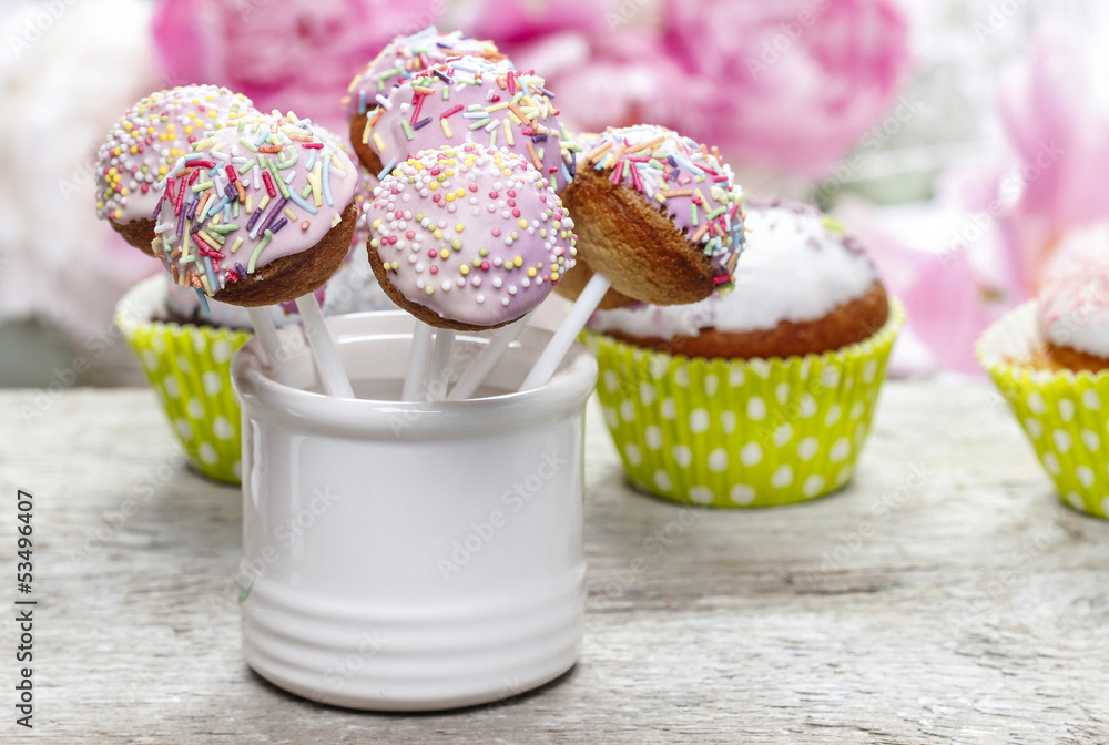 Pastel cake pops and cupcakes on rustic wooden table Pastel cake pops and cupcakes on rustic wooden table