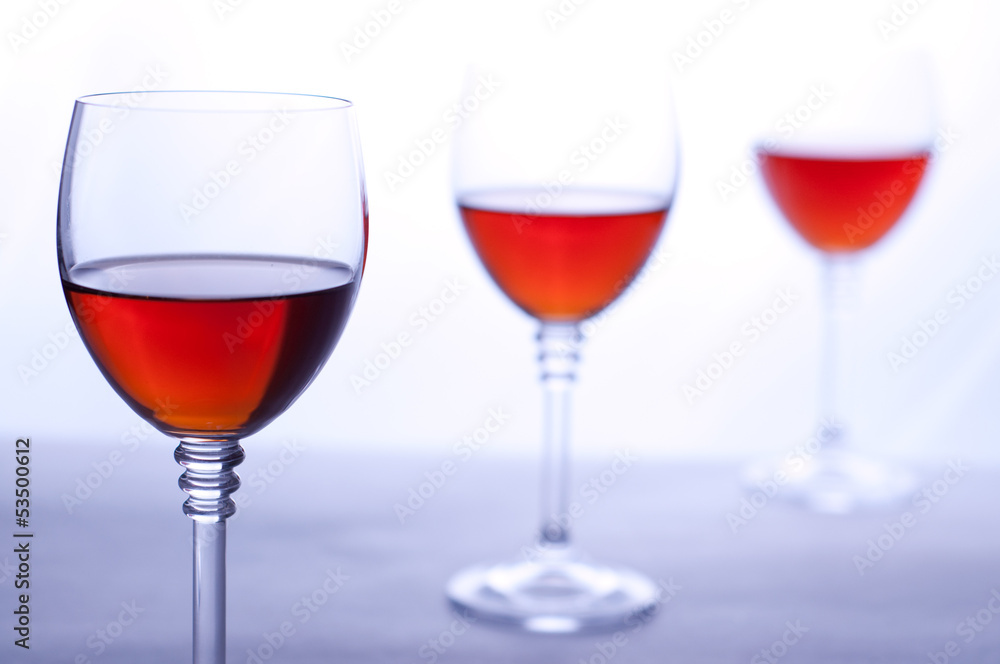 Three transparent wineglasses with rose wine. White background