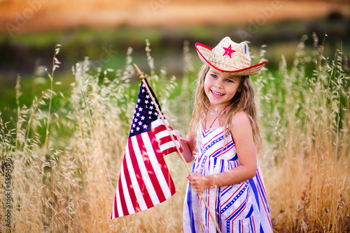 Happy adorable little girl smiling and waving American flag outs