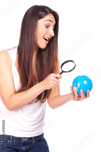 Pretty female holding a globe and using a magnifying glass while