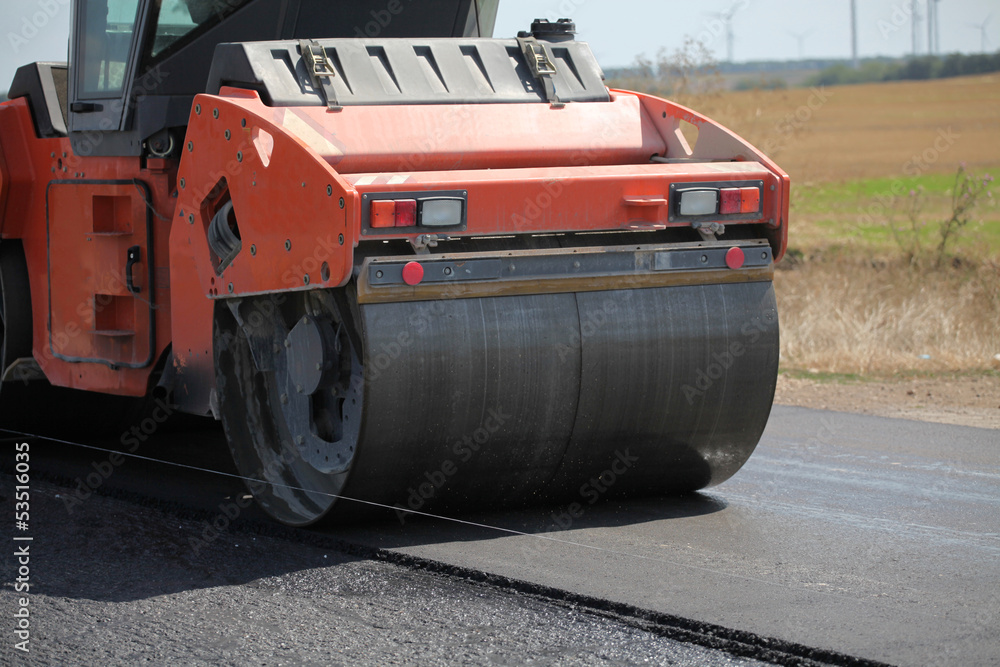 Large road-roller paving a road. Road construction Large road-roller paving a road. Road construction