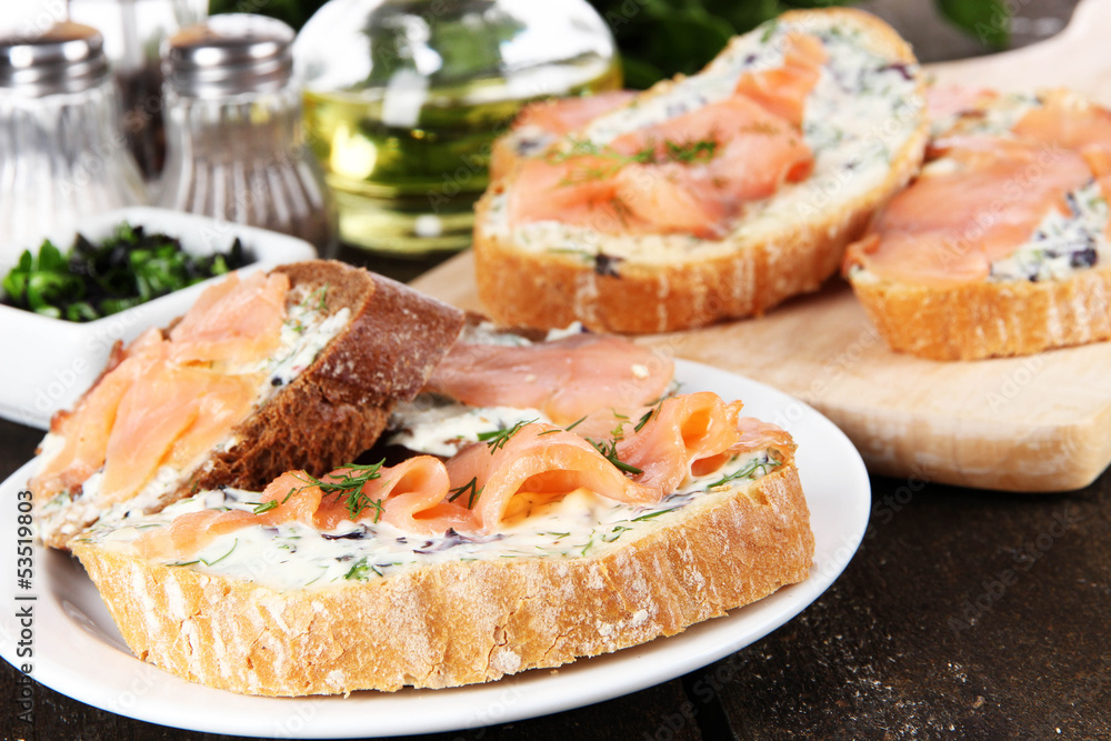 Fish sandwiches on cutting board and plate on wooden table Fish sandwiches on cutting board and plate on wooden table