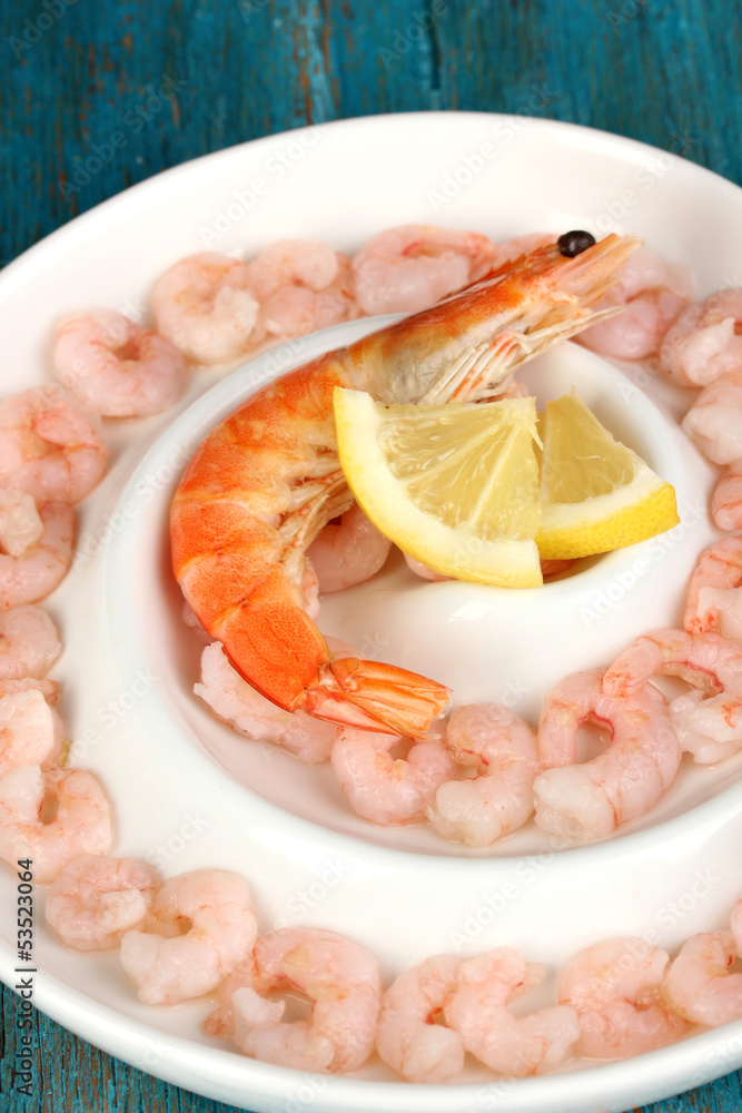Shrimps with lemon on plate on blue wooden table close-up Shrimps with lemon on plate on blue wooden table close-up