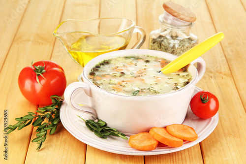 Nourishing soup in pink pan on wooden table close-up