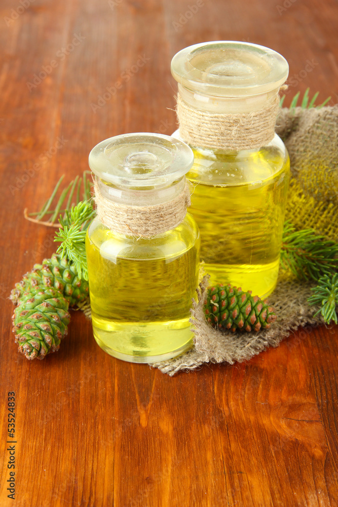 Bottles of fir tree oil and green cones on wooden background Bottles of fir tree oil and green cones on wooden background
