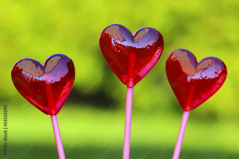 Red lollipops in heart shape, on fresh green grass