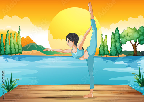 A girl performing yoga along the river in a sunset scenery