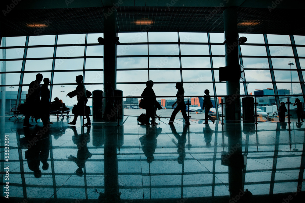 Silhouettes of people with luggage walking at airport