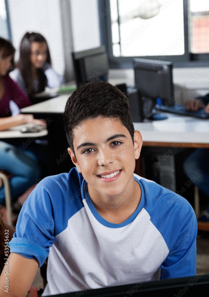 Fototapeta premium Happy Teenage Schoolgirl Sitting In Computer Lab