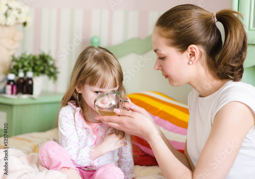 mother gives to drink to the sick child