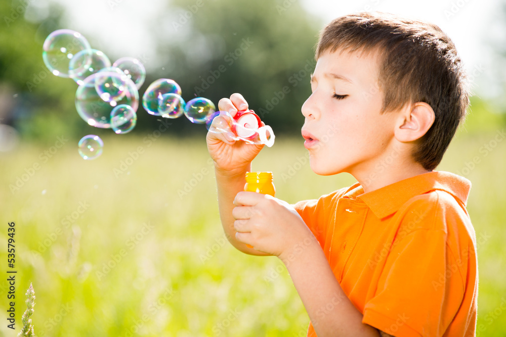 Young caucasian boy blowing the soap bubbles on nature Young caucasian boy blowing the soap bubbles on nature