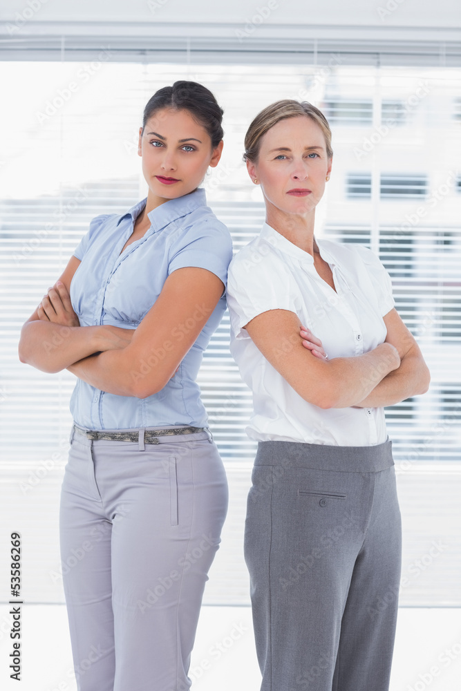 Fototapeta premium Serious businesswomen standing back to back