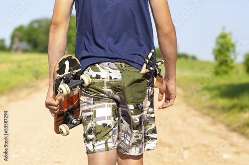 Boy with skateboard and slingshot in pocket