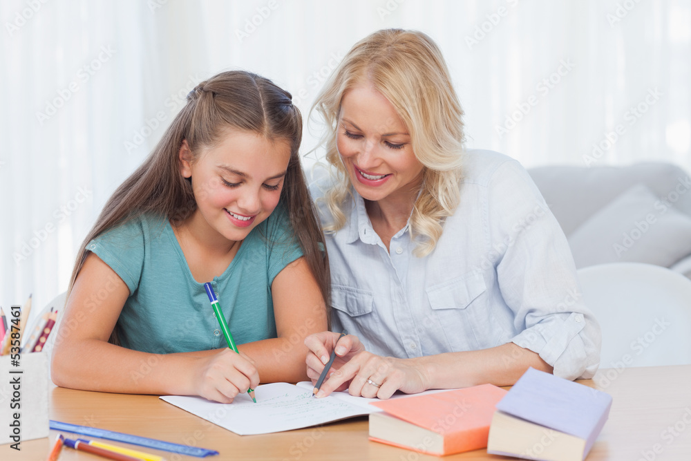 Smiling mother helping daughter with homework Smiling mother helping daughter with homework