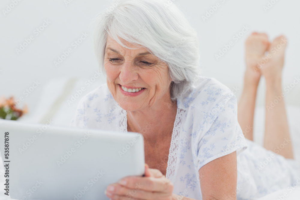 Woman lying on bed and using a tablet Woman lying on bed and using a tablet