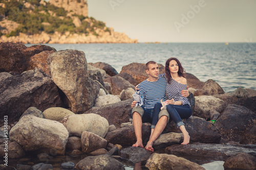 Family in striped shirts on the rocks near the sea