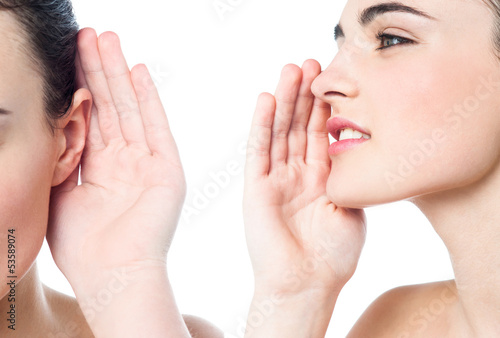 Pretty girl sharing a secret with her friend