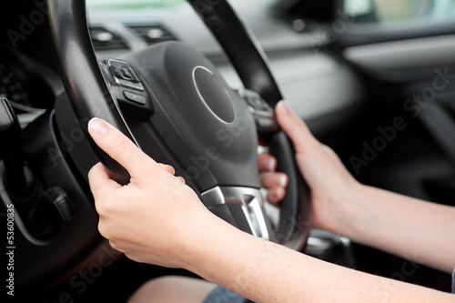woman hands holding steering wheel in luxury car