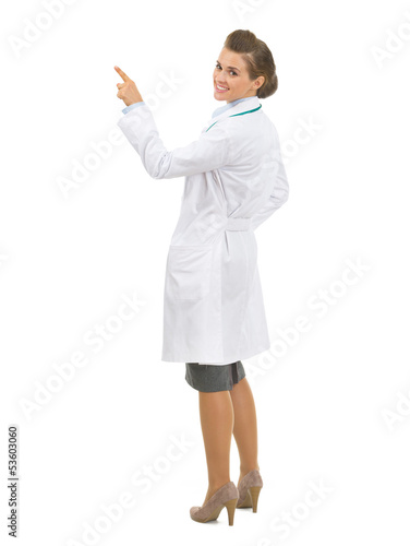Full length portrait of doctor woman pointing up on copy space