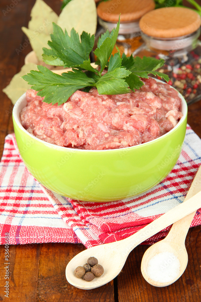 Bowl of raw ground meat with spices on wooden table Bowl of raw ground meat with spices on wooden table