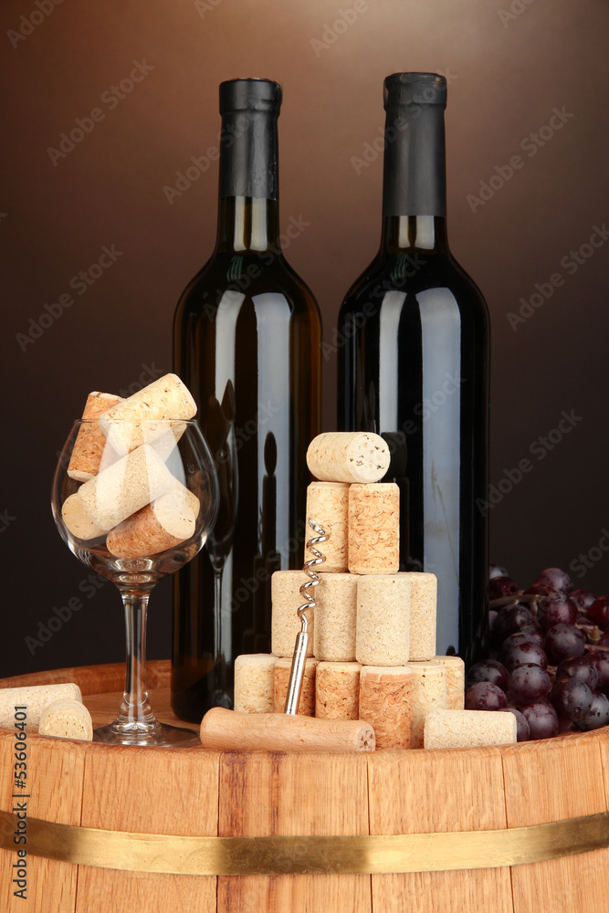 Naklejka premium Wine and corks on barrel on brown background