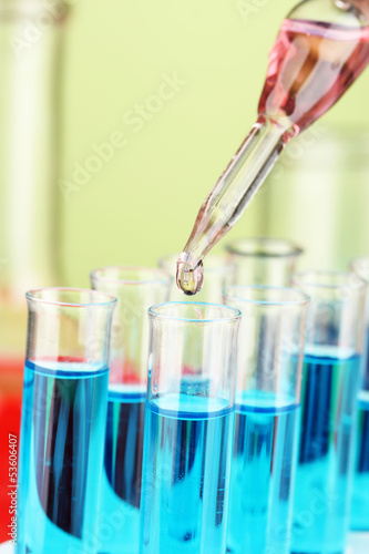 Laboratory pipette with drop of color liquid over glass test
