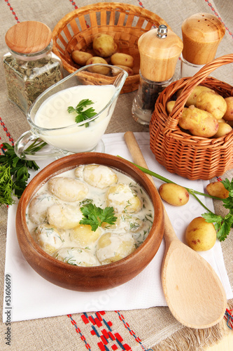 Tender young potatoes with sour cream and herbs in wooden bowl