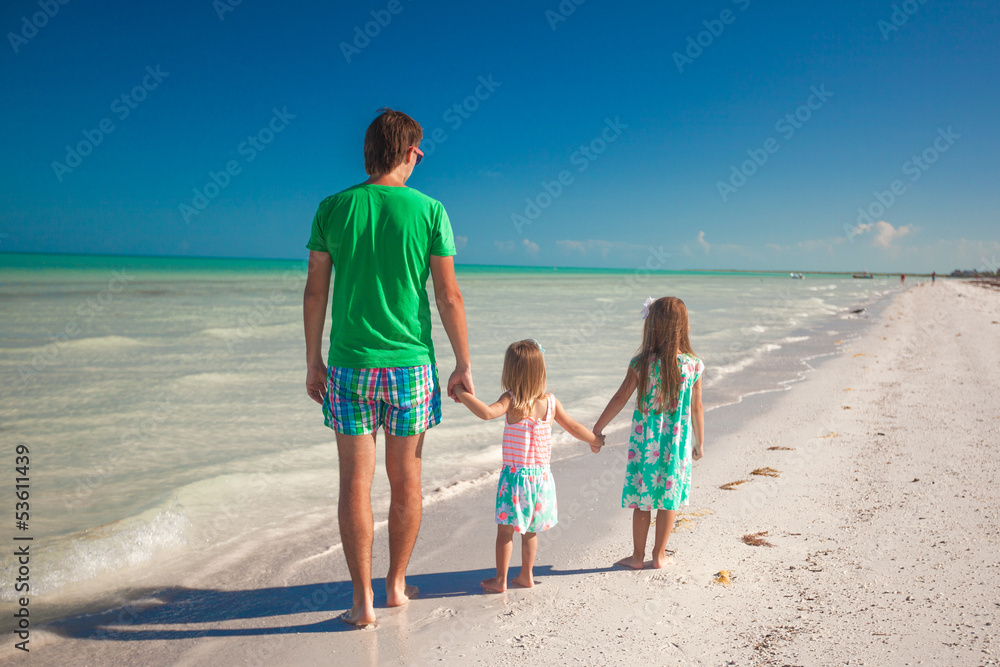 Back view of happy father with his two kids walking on tropical Back view of happy father with his two kids walking on tropical