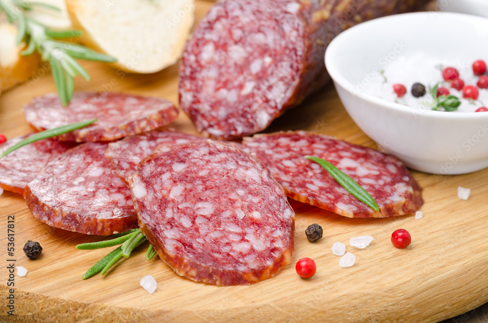 Italian salami sliced into pieces on wooden cutting board Italian salami sliced into pieces on wooden cutting board