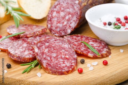 Italian salami sliced ​​into pieces on wooden cutting board
