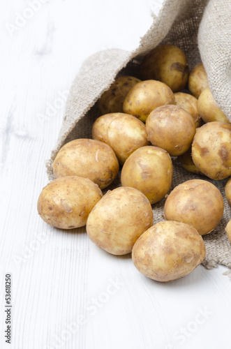 new potatoes in a sack on a white wooden board