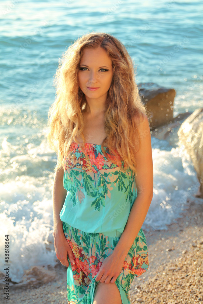 Beautiful woman with wavy hair on sea beach background, outdoors Beautiful woman with wavy hair on sea beach background, outdoors