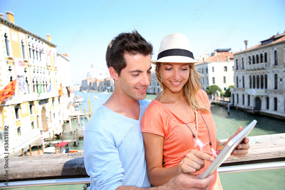 Couple using tablet on the Academia Bridge in Venice, Italy