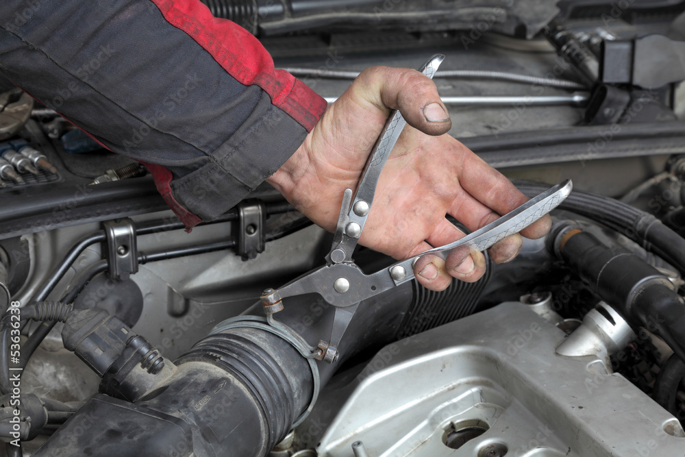 Mechanic fix hose clamp with pliers tool at car engine