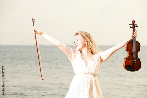 Happy blonde girl with a violin outdoor