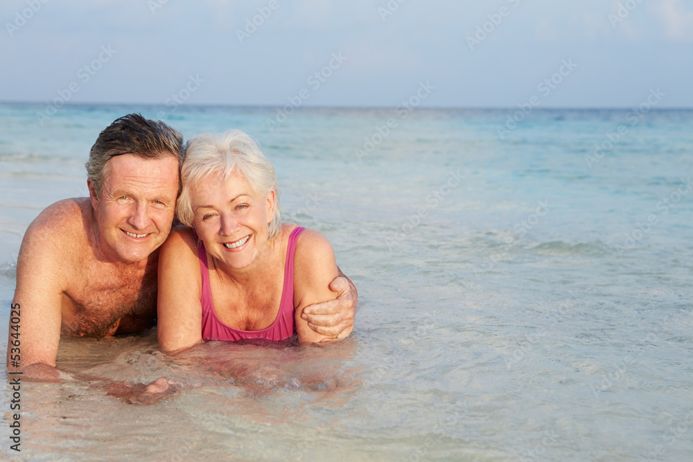 Romantic Senior Couple Lying In Sea On Beach Holiday Romantic Senior Couple Lying In Sea On Beach Holiday