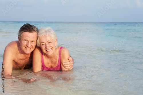 Romantic Senior Couple Lying In Sea On Beach Holiday © Monkey Business