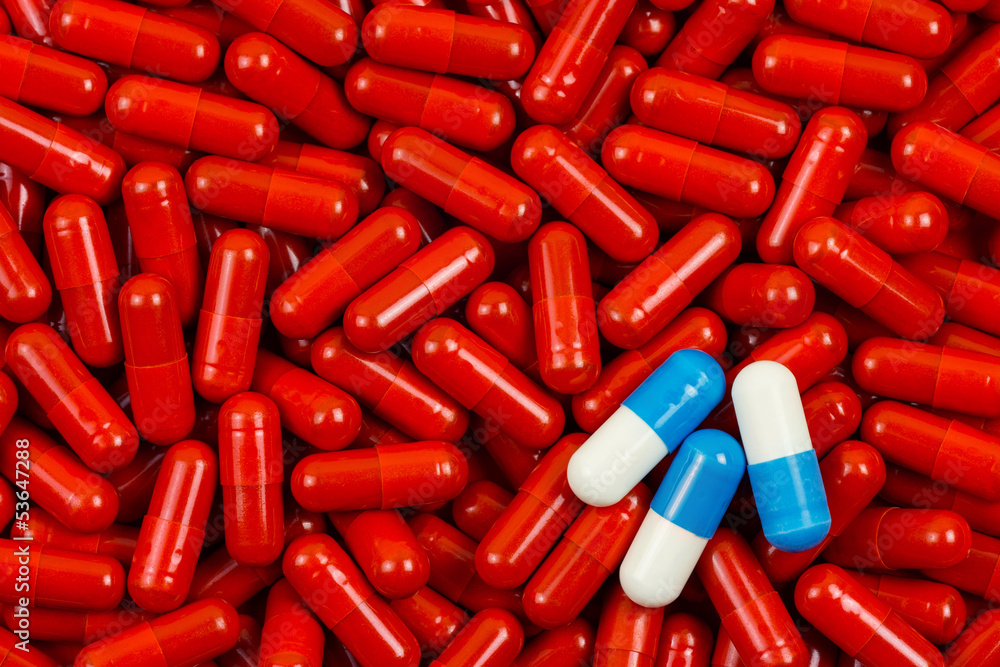 Blue and white pills on background of red pills Blue and white pills on background of red pills