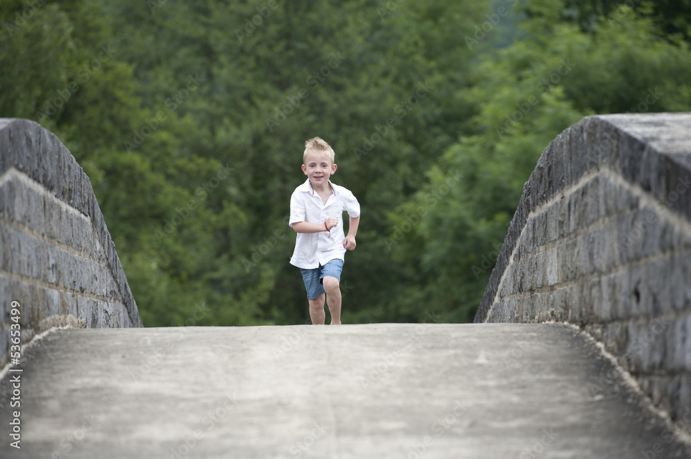 summer time : little boy running on a bridge summer time : little boy running on a bridge