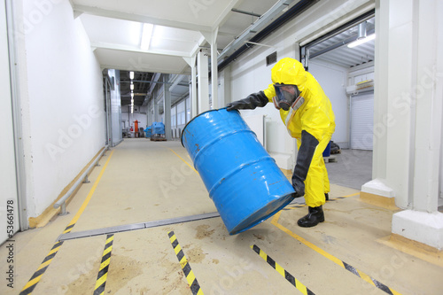 Foto technician in uniform rolling barrel with hazardous substance