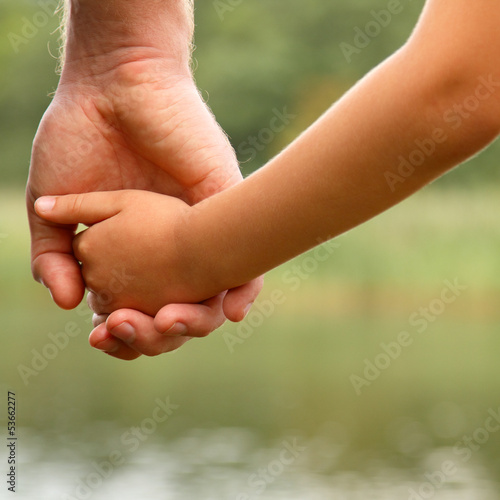 father's hand lead his child son in summer nature background © Khorzhevska